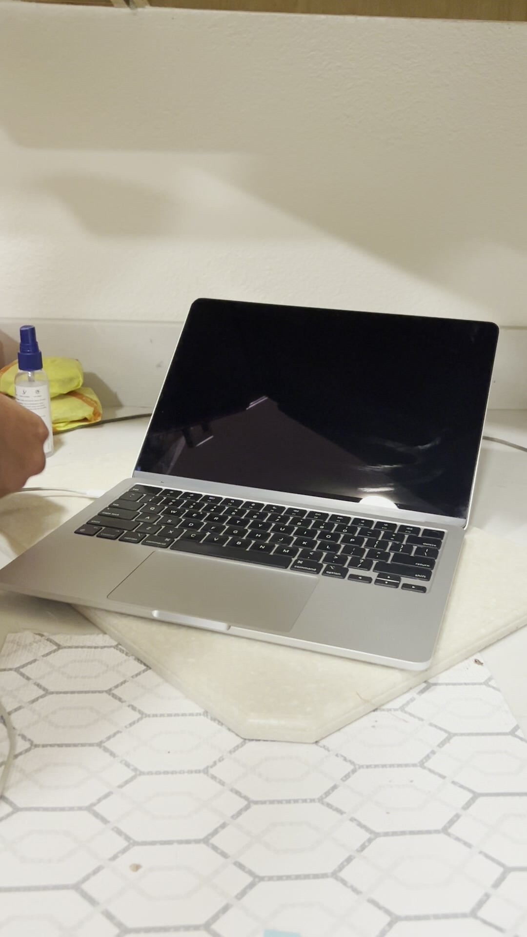 MacBook Pro on hexagonal Artisan tile · screen off · blue spray bottle + yellow microfiber kit · DFU clean protocol · McMorrow Rd · KenshoTek · 925